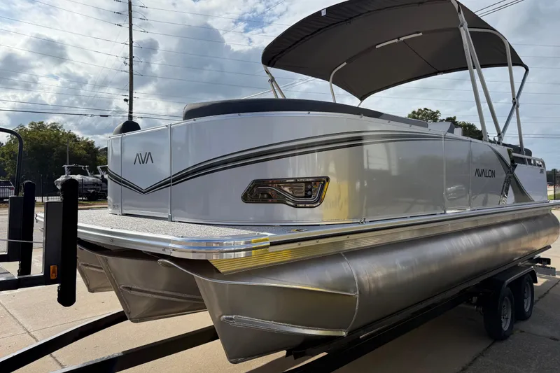 Slide: The Image of 2026 Avalon LSZ Quad Lounger Shift pontoon boat on trailer, featuring sleek design and canopy. - 5