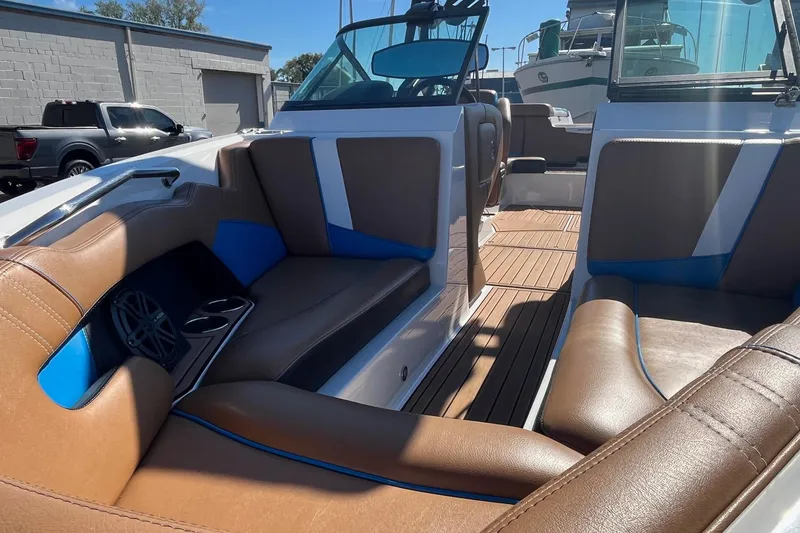 Slide: The Image of 2016 Nautique Super Air Nautique 230 interior with brown and blue seating, wood flooring. - 10