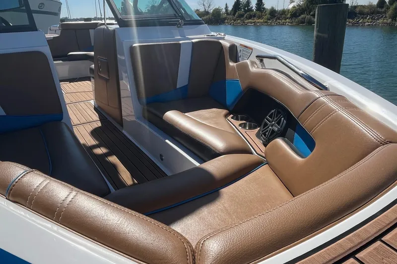 Slide: The Image of 2016 Nautique Super Air Nautique 230 interior with brown and blue seating, cup holders, and speaker. - 11