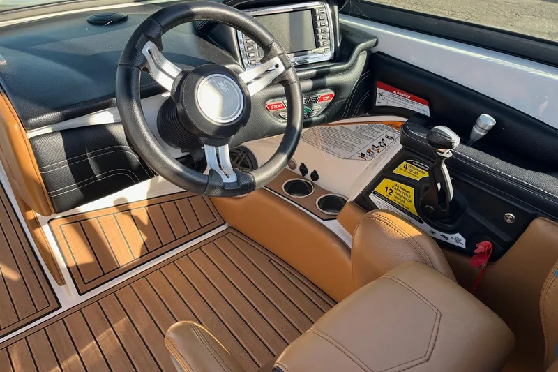 Slide: The Image of Interior of 2016 Nautique Super Air Nautique 230 boat, featuring steering wheel and control panel. - 2