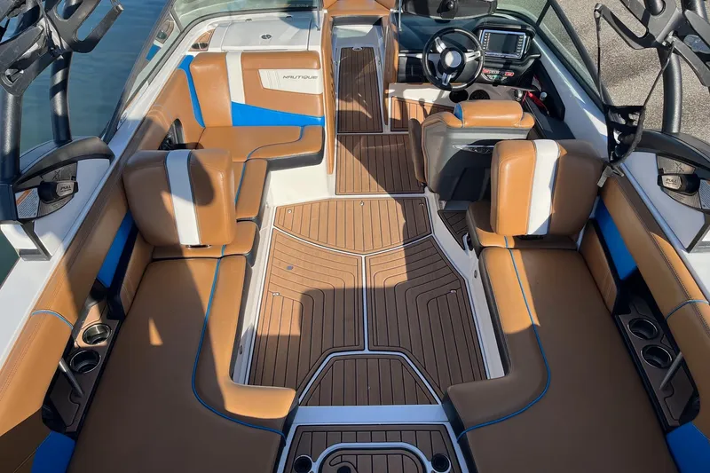 Slide: The Image of 2016 Nautique Super Air Nautique 230 interior with tan and blue seating, sleek design. - 4