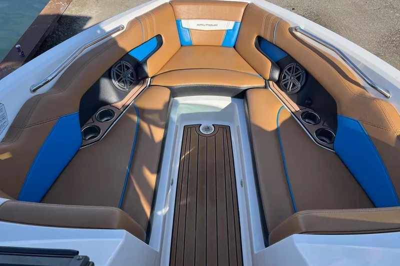 Slide: The Image of 2016 Nautique Super Air Nautique 230 interior with brown and blue seating, cup holders, and speakers. - 5