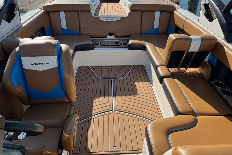 Slide: The Image of 2016 Nautique Super Air Nautique 230 interior with brown and blue seating, wood-style flooring. - 6