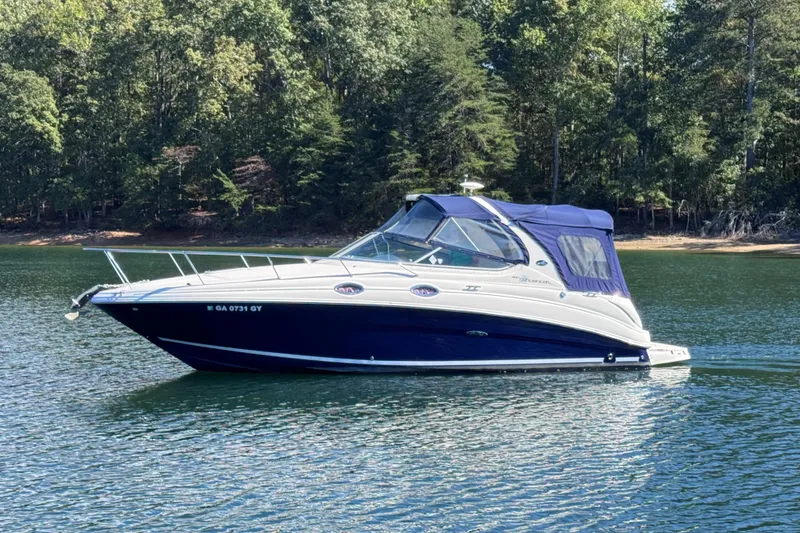 The Image of 2005 Sea Ray 280 Sundancer boat on a serene lake with forested background. - 0