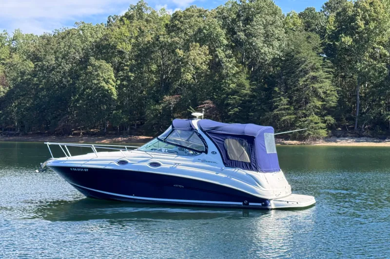 Slide: The Image of 2005 Sea Ray 280 Sundancer boat on a serene lake with forested background. - 14