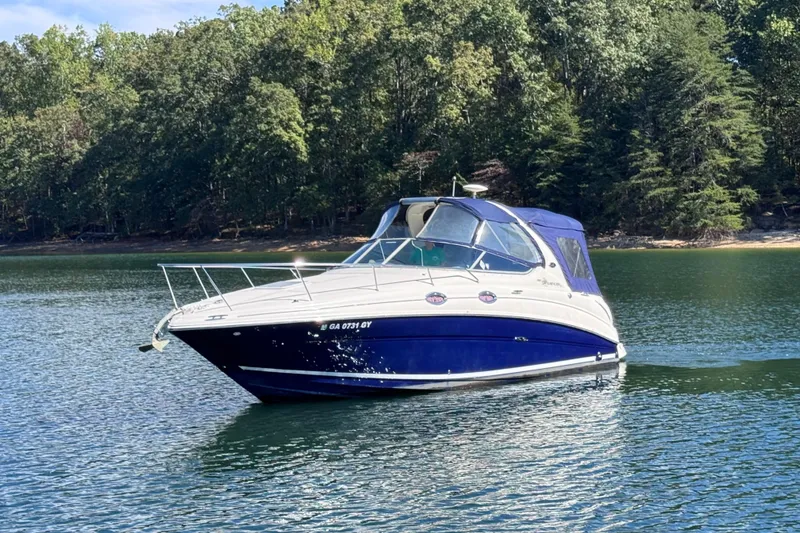 Slide: The Image of 2005 Sea Ray 280 Sundancer boat cruising on a serene lake with forested shoreline. - 2