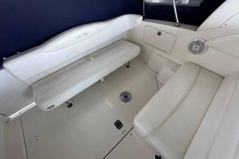 Slide: The Image of 2005 Sea Ray 280 Sundancer interior seating area with white upholstery and storage compartment. - 20