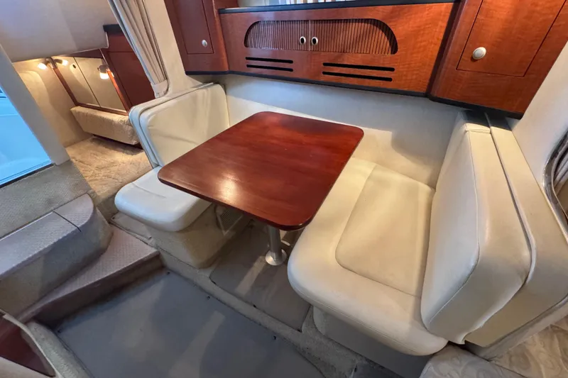 Slide: The Image of 2005 Sea Ray 280 Sundancer cabin with cozy dining area and wooden table. - 23