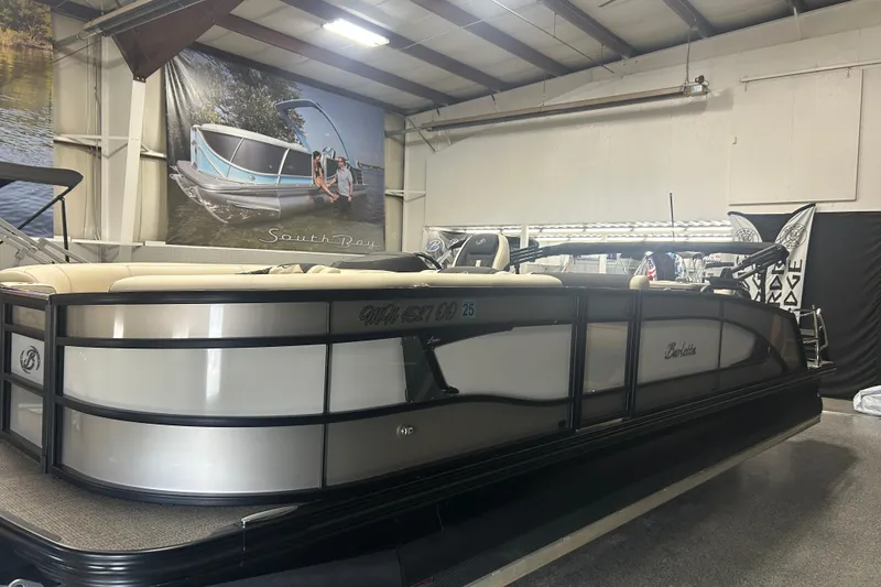 Slide: The Image of 2025 Barletta Lusso 25UE pontoon boat with Mercury outboard motor, displayed indoors. - 3