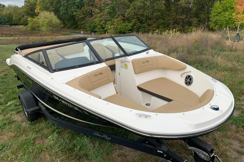Slide: The Image of 2019 Sea Ray SPX 190 boat on trailer, parked on grassy area with trees in background. - 2