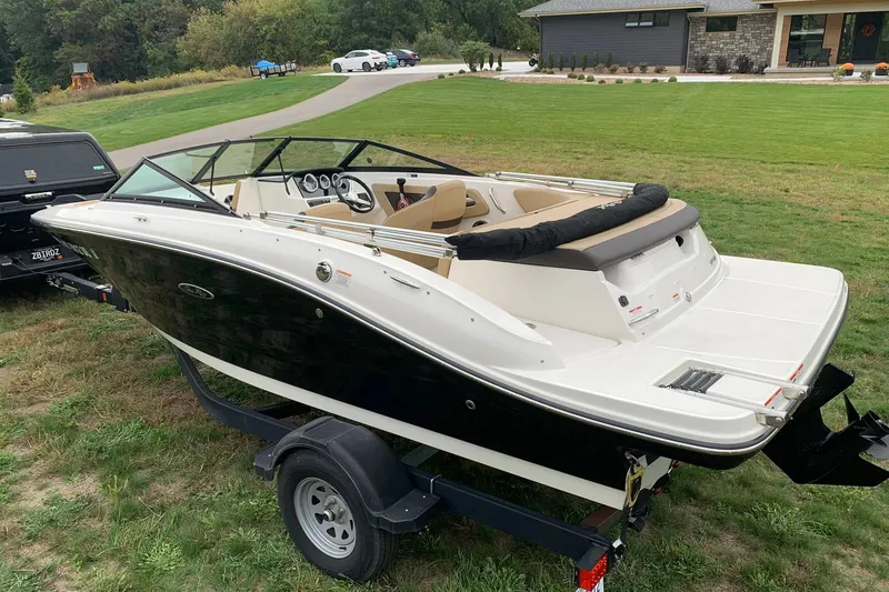 Slide: The Image of 2019 Sea Ray SPX 190 boat on trailer, parked on grass near a modern house. - 4