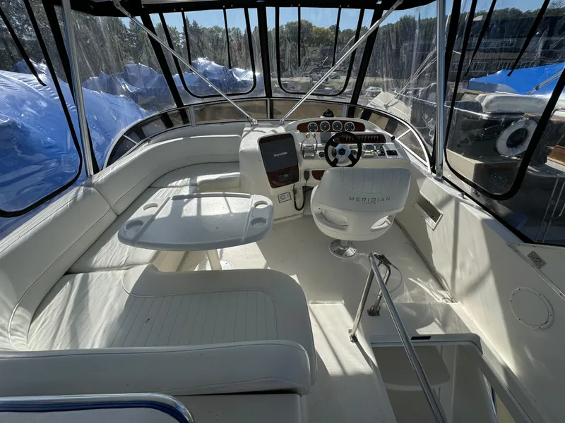 Slide: The Image of 2004 Meridian 381 Sedan boat interior with helm, seating, and table under clear canopy. - 8