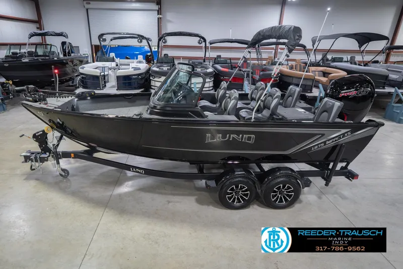 The Image of 2026 Lund 1875 Impact XS boat in showroom, black exterior, on trailer. - 2
