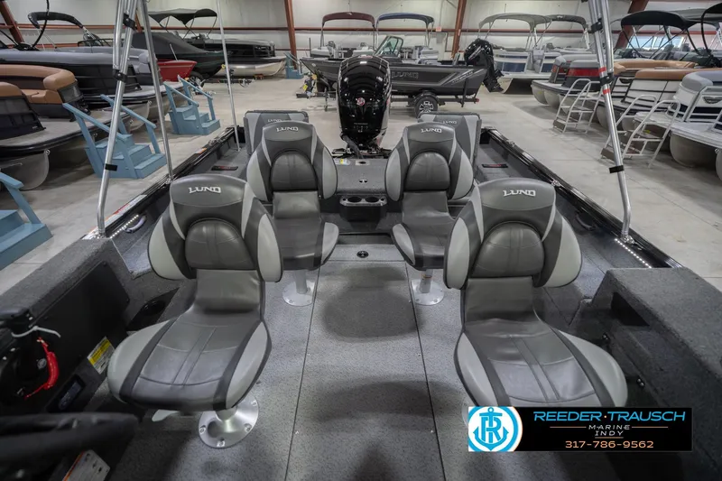 Slide: The Image of 2026 Lund 1875 Impact XS boat interior with four gray seats in a showroom. - 20