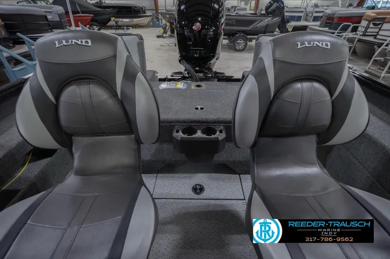 Slide: The Image of 2026 Lund 1875 Impact XS boat interior with two seats and motor, in showroom. - 21