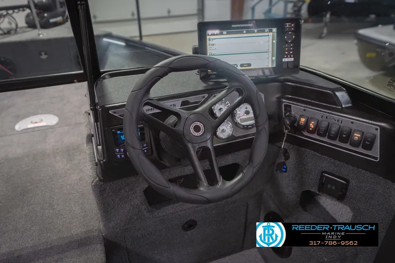 Slide: The Image of 2026 Lund 1875 Impact XS boat dashboard with steering wheel and electronic controls. - 34
