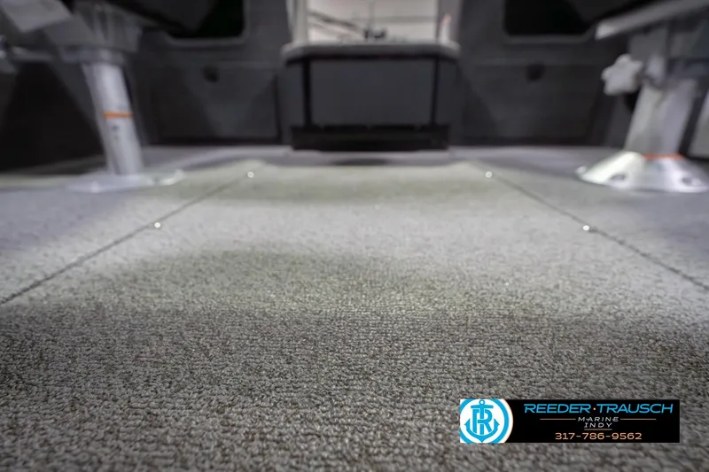Slide: The Image of 2026 Lund 1875 Impact XS boat interior with carpeted flooring, Reeder-Trausch Marine logo visible. - 48