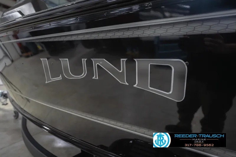 Slide: The Image of 2026 Lund 1875 Impact XS boat, sleek black exterior with logo, displayed at Reeder-Trausch Marine. - 58
