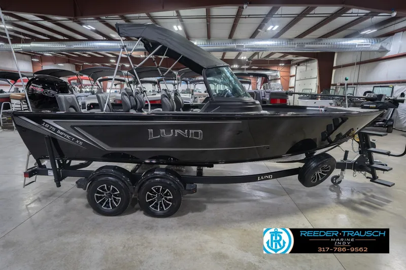Slide: The Image of 2026 Lund 1875 Impact XS boat in showroom, side view with trailer. - 7