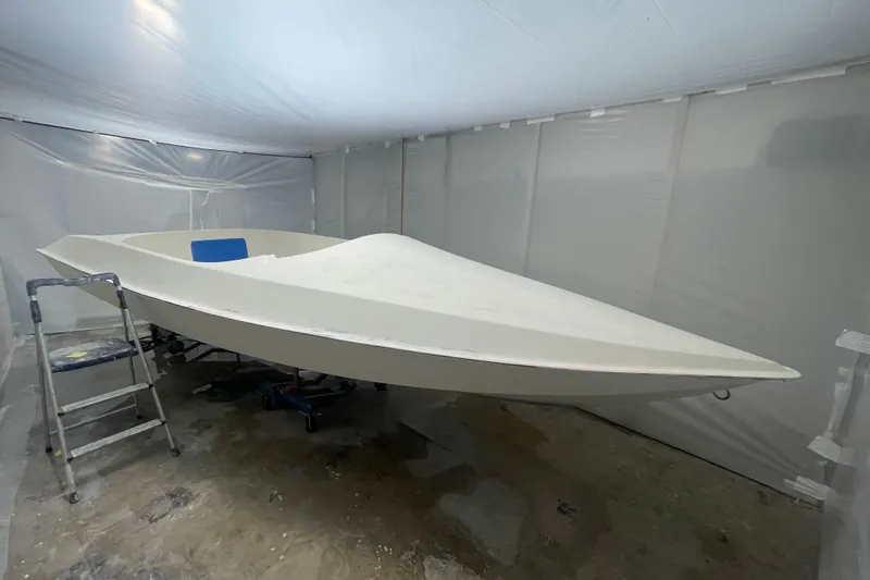 Slide: The Image of 1985 JJM VS boat hull in a workshop, surrounded by protective plastic sheeting. - 12