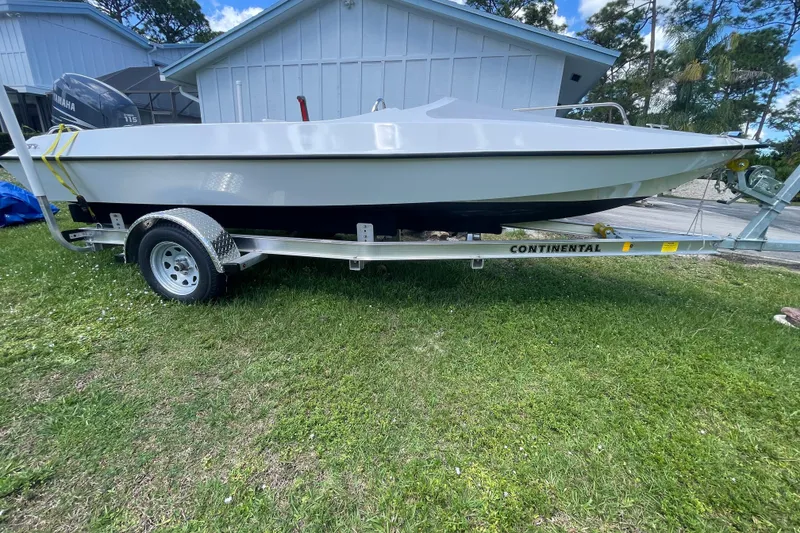 Slide: The Image of White JJM VS 1985 boat on a Continental trailer, parked on grass. - 9