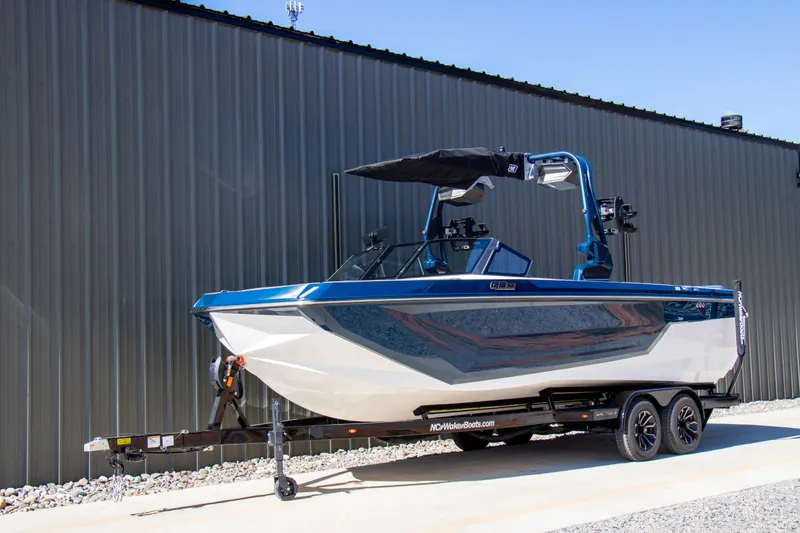 Slide: The Image of 2026 Nautique Super Air Nautique GS24 boat on trailer, blue and white design. - 2