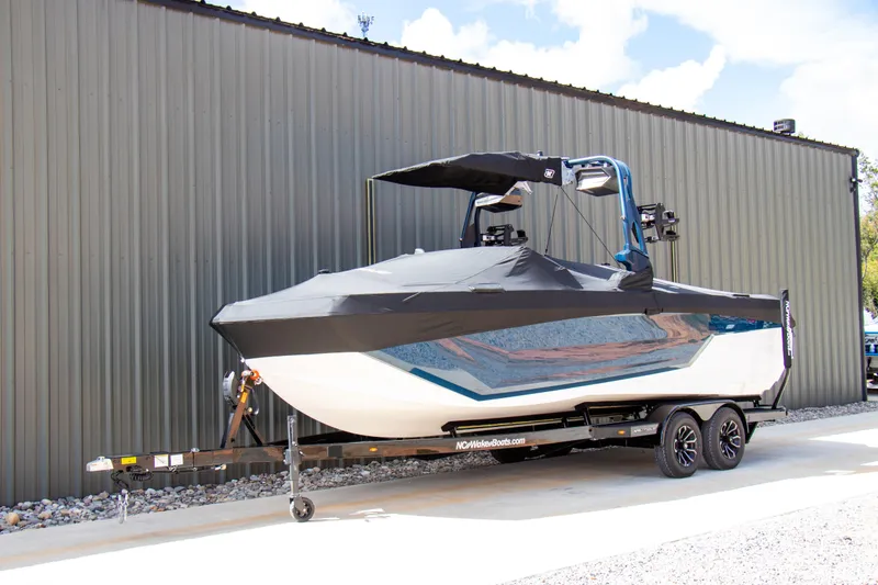 Slide: The Image of 2026 Nautique Super Air Nautique GS24 boat on trailer, covered and parked outdoors. - 5
