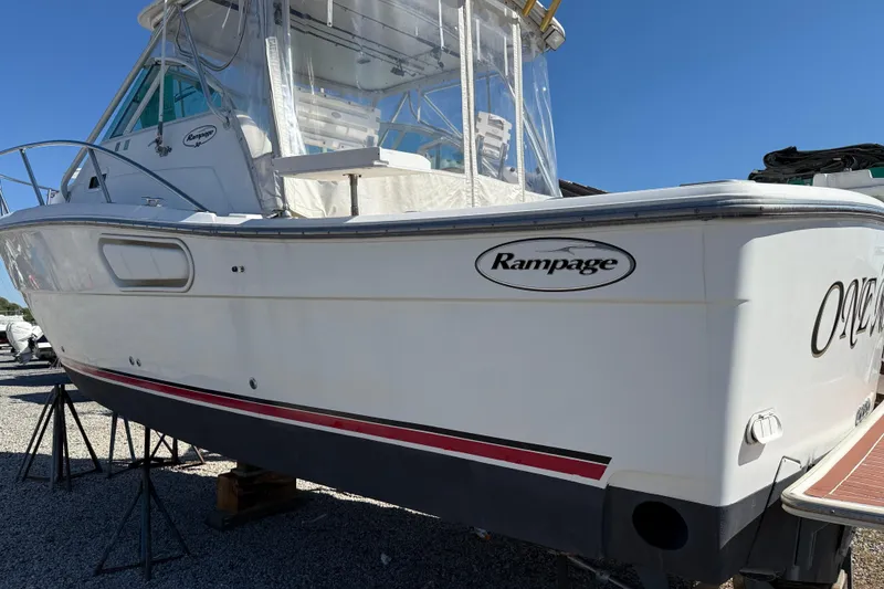 The Image of 2002 Rampage 30 Express boat on stands, white hull, clear sky background. - 0