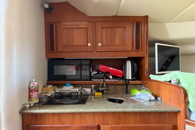 Slide: The Image of Compact kitchen area in a 2002 Rampage 30 Express boat with wooden cabinets and appliances. - 22