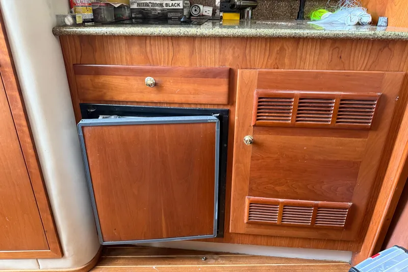 Slide: The Image of Wooden cabinetry with open mini fridge in 2002 Rampage 30 Express boat interior. - 23