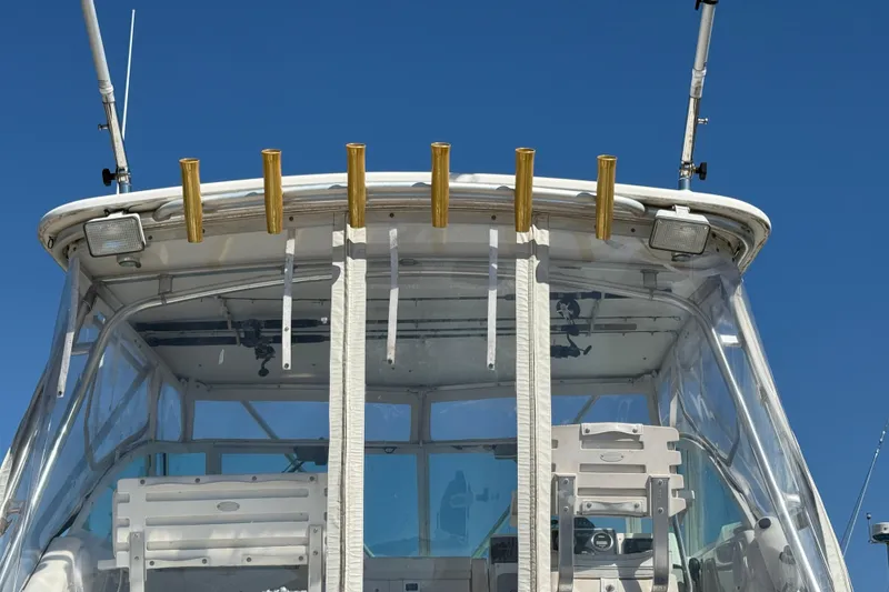 Slide: The Image of 2002 Rampage 30 Express boat cockpit with fishing rod holders and clear canopy under blue sky. - 3