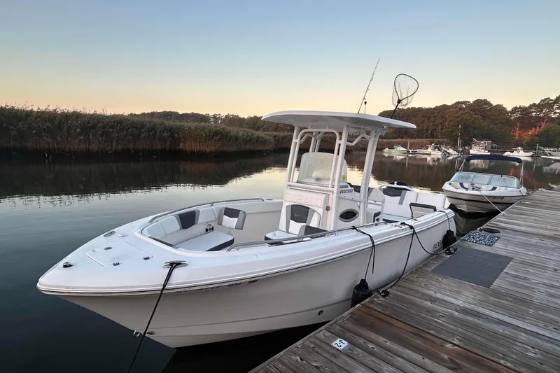 The Image of 2020 Robalo R230 Center Console boat docked on calm water at sunset. - 0