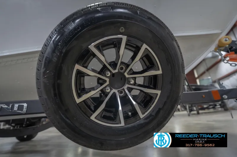 Slide: The Image of 2026 Lund 1675 Adventure Sport trailer wheel in a showroom setting. - 64