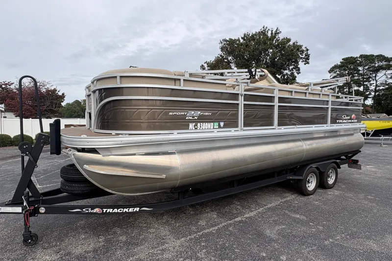 The Image of 2024 Sun Tracker SportFish 22 DLX pontoon boat on trailer, parked outdoors. - 0