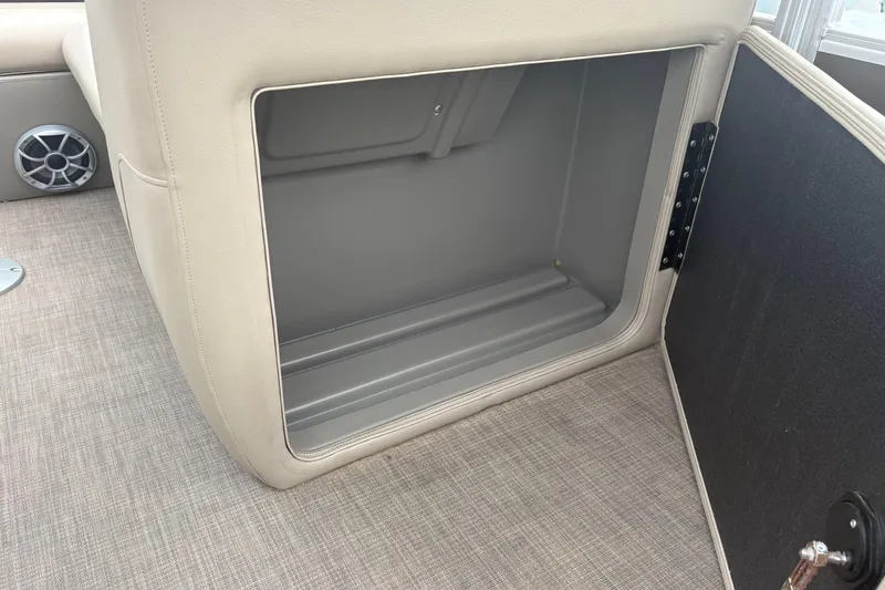 Slide: The Image of 2024 Sun Tracker SportFish 22 DLX storage compartment with beige interior and speaker detail. - 16