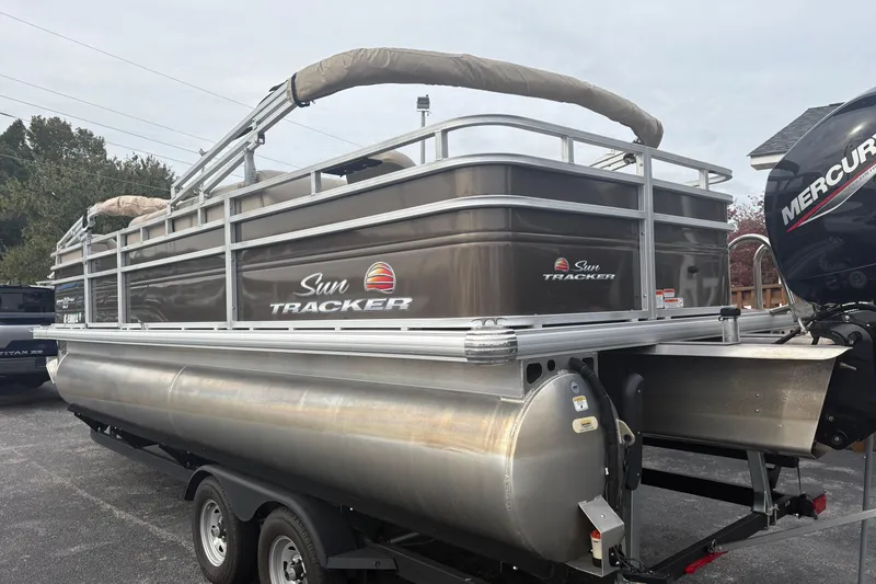 Slide: The Image of 2024 Sun Tracker SportFish 22 DLX pontoon boat on trailer, featuring Mercury outboard motor. - 2
