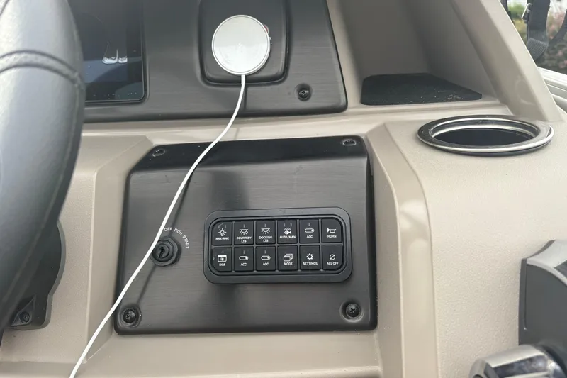 Slide: The Image of Control panel of 2024 Sun Tracker SportFish 22 DLX boat with various switches and cup holder. - 21