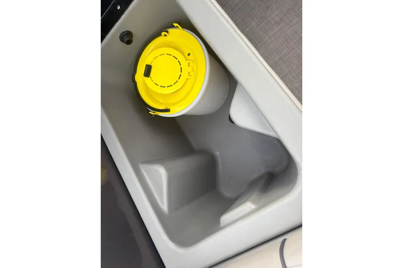Slide: The Image of 2024 Sun Tracker SportFish 22 DLX storage compartment with yellow-lidded container. - 26