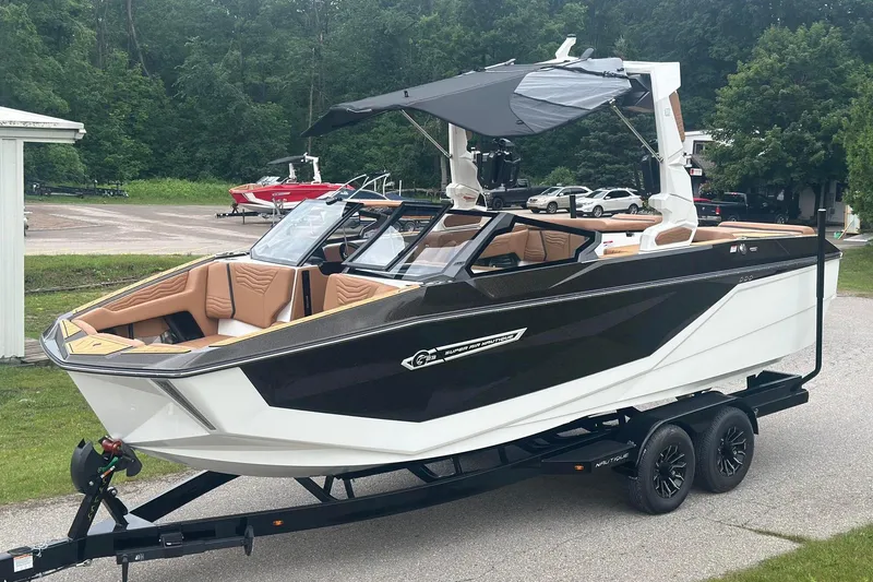 Slide: The Image of 2025 Nautique Super Air Nautique G23 boat on trailer, black and white design, parked outdoors. - 1