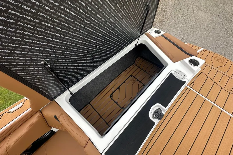 Slide: The Image of 2025 Nautique Super Air Nautique G23 storage compartment with open lid and cup holders. - 14