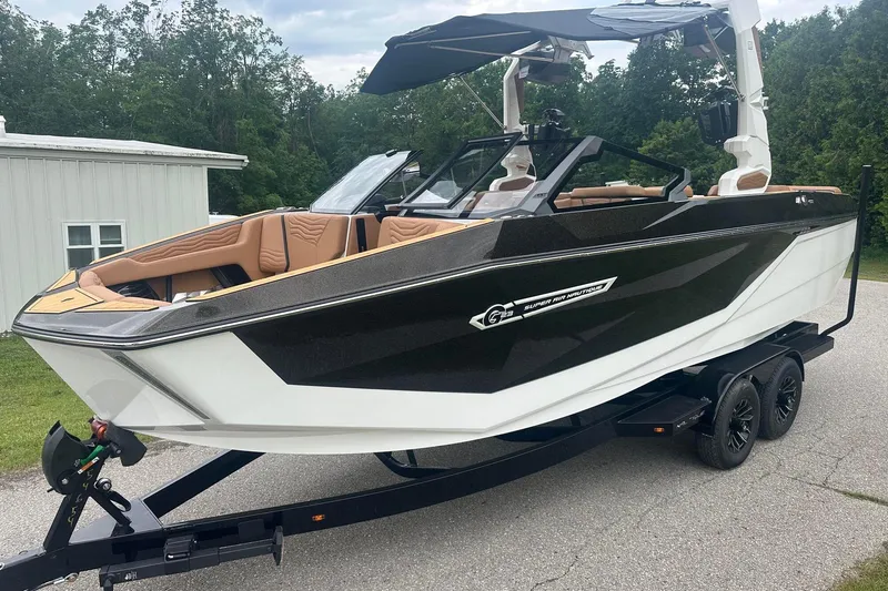 Slide: The Image of 2025 Nautique Super Air Nautique G23 boat on trailer, sleek design, parked outdoors. - 2