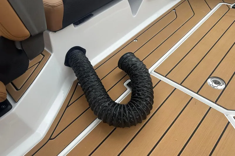Slide: The Image of 2025 Nautique Super Air Nautique G23 interior with black hose on teak-style flooring. - 20