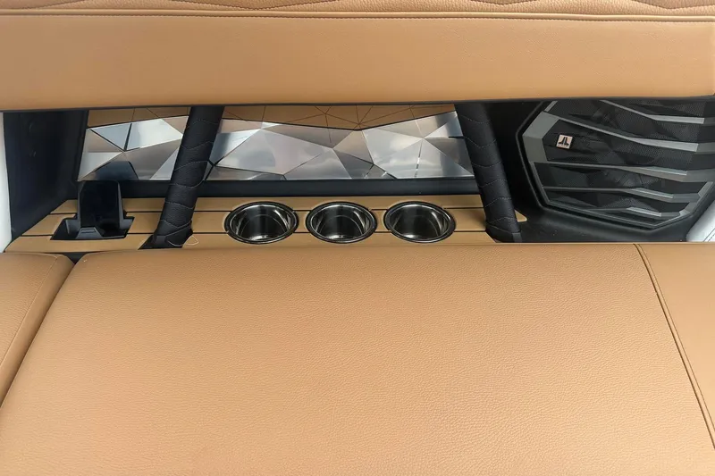Slide: The Image of 2025 Nautique Super Air Nautique G23 interior with tan upholstery and cup holders. - 21