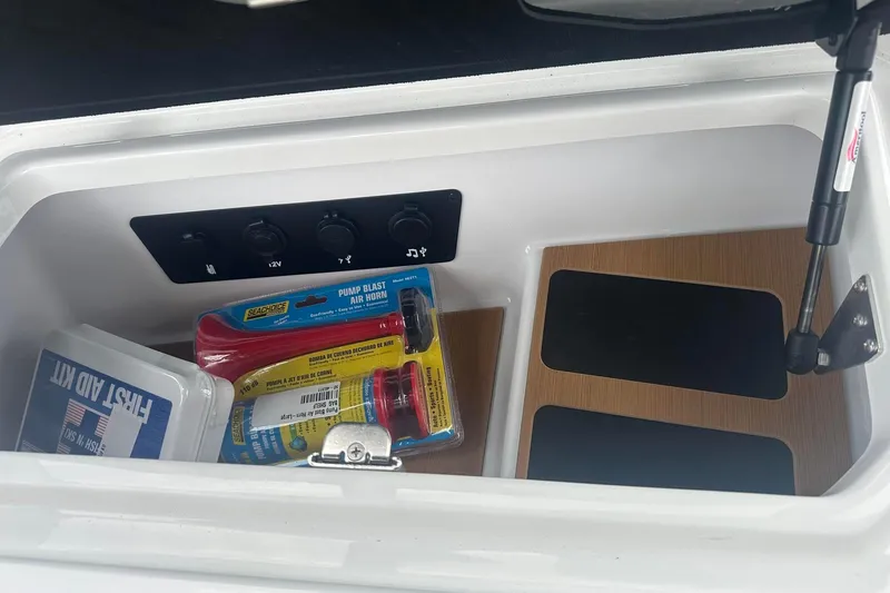 Slide: The Image of Storage compartment in 2025 Nautique Super Air Nautique G23 with first aid kit and air horn. - 23