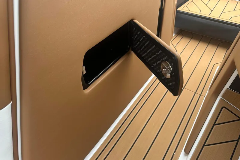 Slide: The Image of 2025 Nautique Super Air Nautique G23 interior storage compartment with tan and black accents. - 24