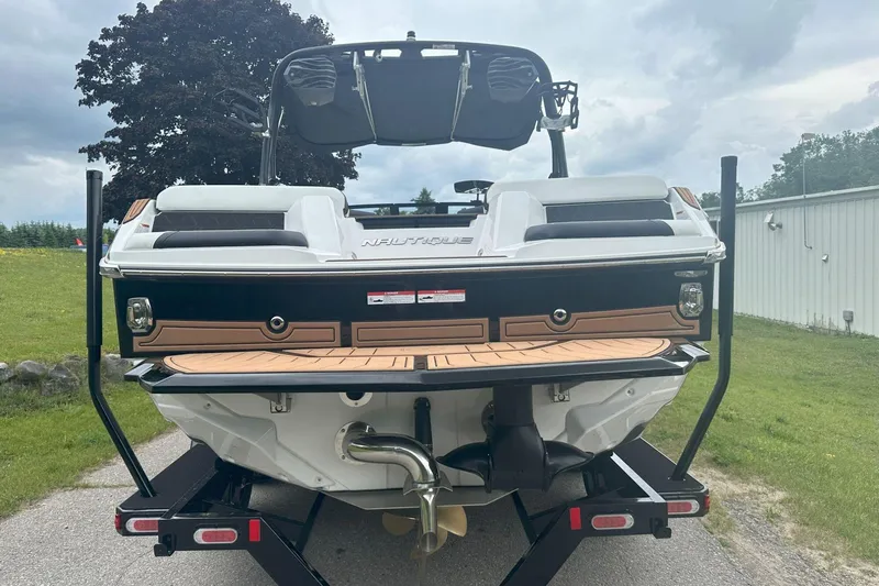 Slide: The Image of 2025 Nautique Super Air Nautique GS22 boat rear view on trailer, outdoors. - 6