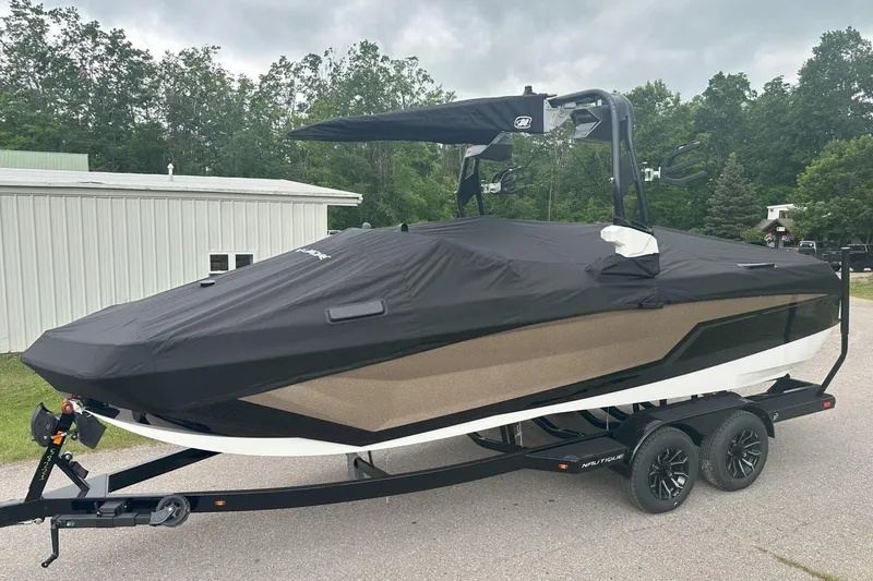 Slide: The Image of 2025 Nautique Super Air Nautique GS22 boat covered on a trailer, parked outdoors. - 9