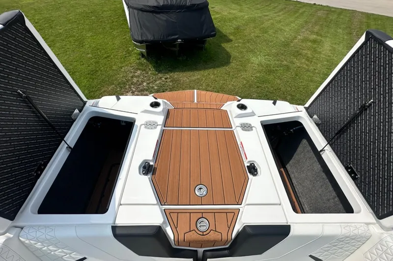 Slide: The Image of 2026 Nautique Super Air Nautique GS22E boat with open storage compartments on grass. - 21