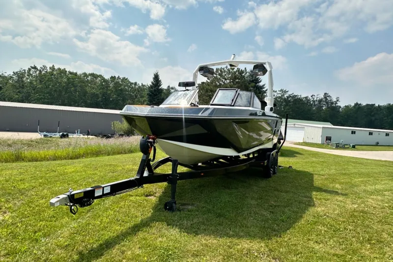 Slide: The Image of 2026 Nautique Super Air Nautique GS22E boat on trailer, parked on grass under blue sky. - 23