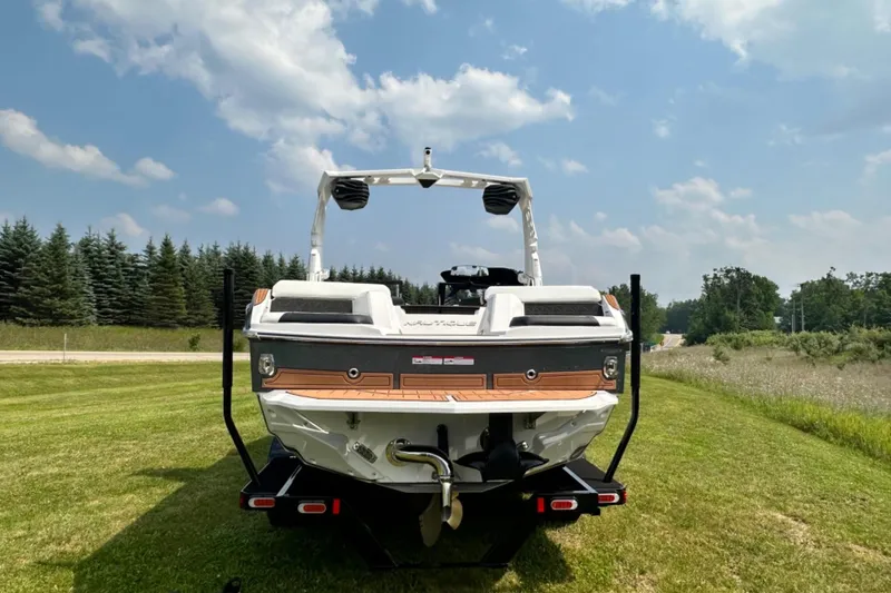 Slide: The Image of 2026 Nautique Super Air Nautique GS22E boat on grassy field under blue sky. - 25